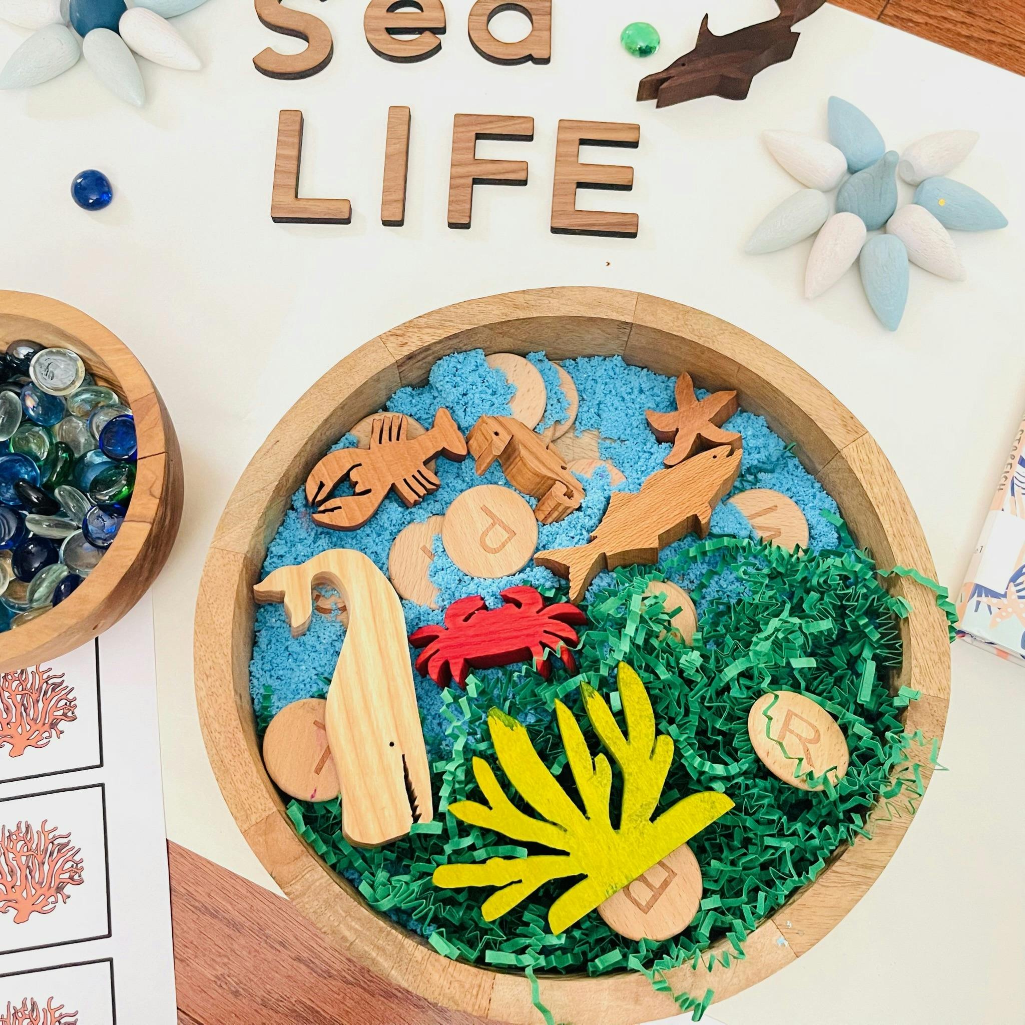 Wooden tray with blue sand and sea animal figures labeled Sea Life