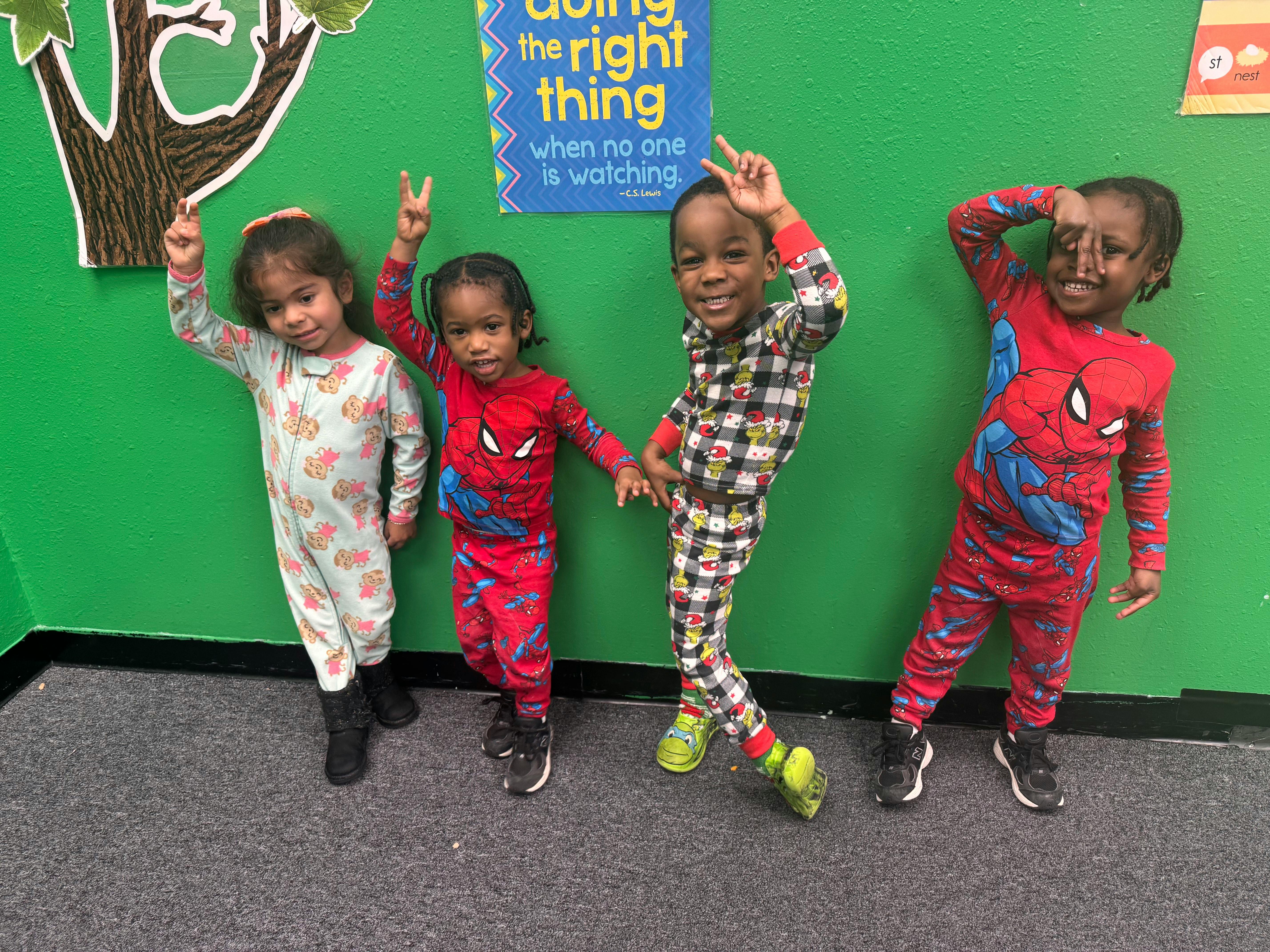 Four children in pajamas making peace signs and other gestures