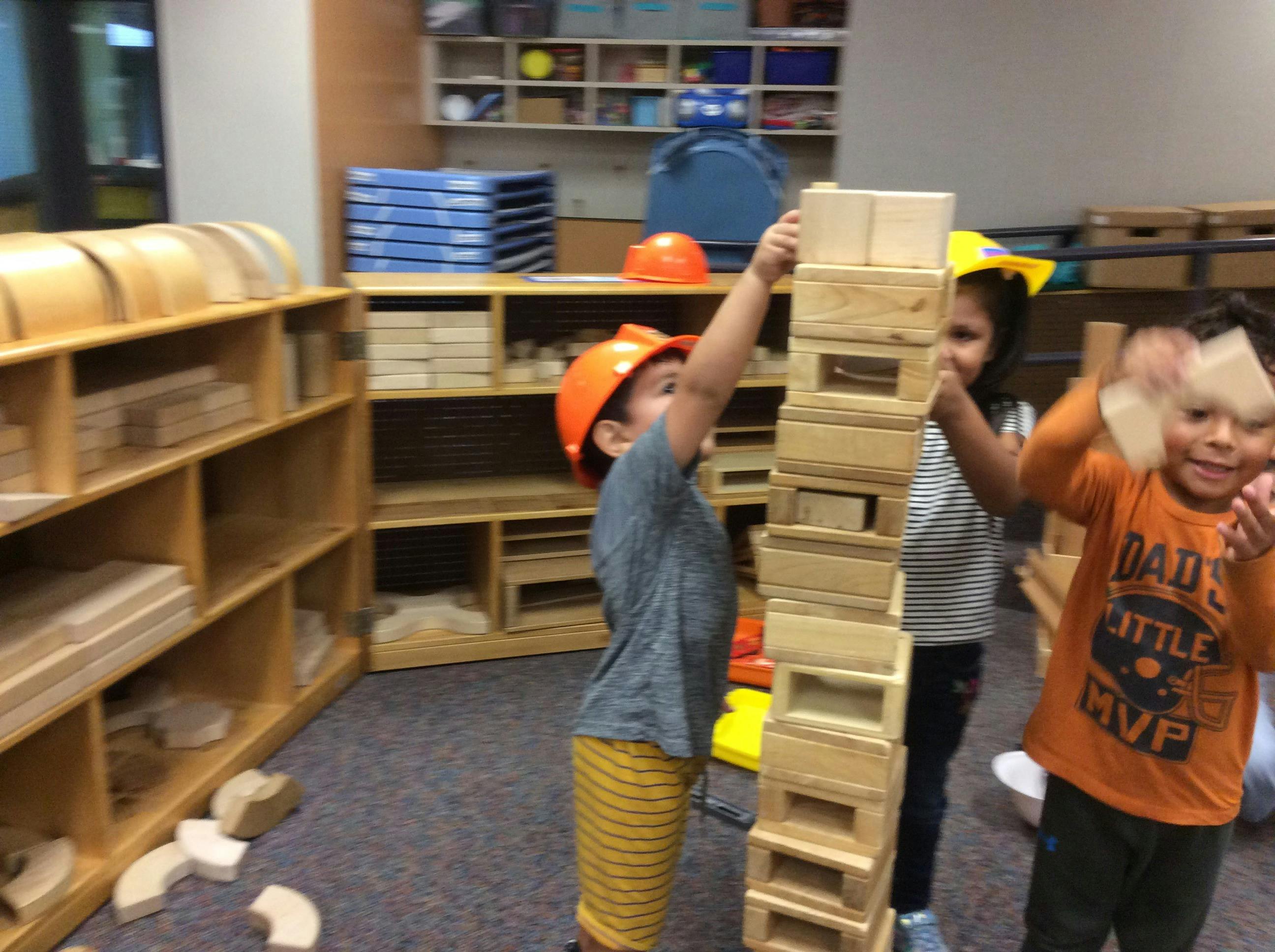 Children building a tall tower with wooden blocks in a classroom
