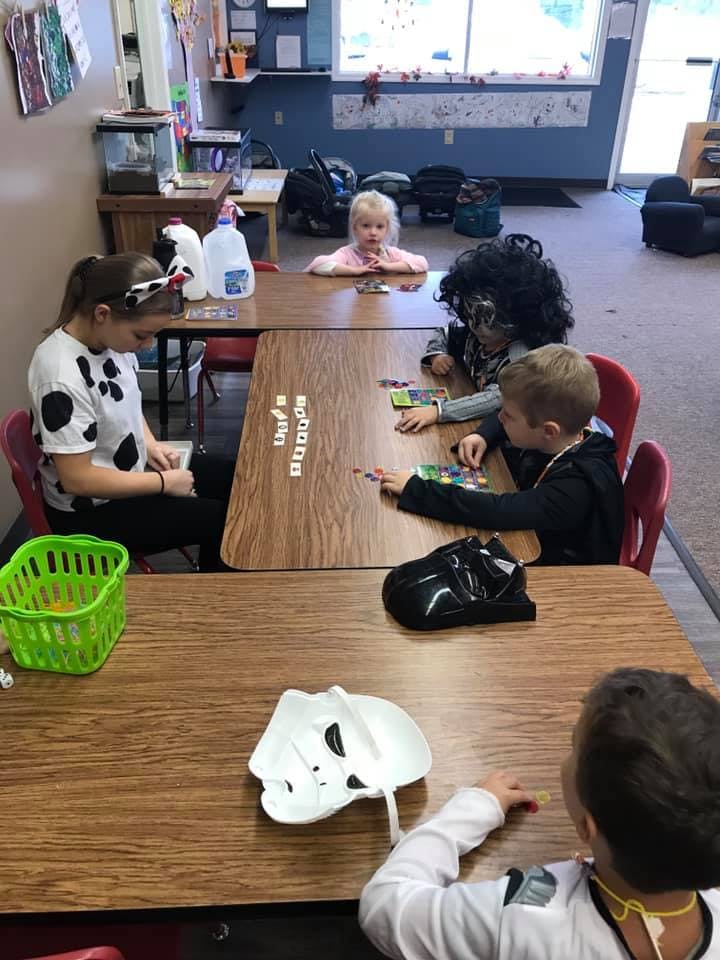 People and children sitting at tables in a classroom