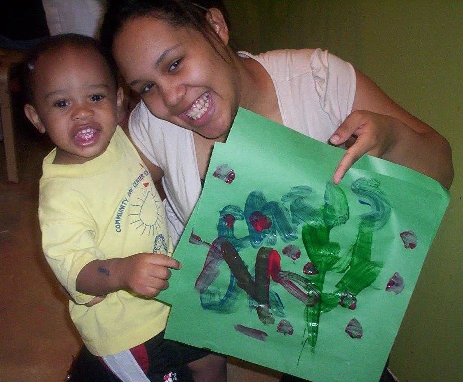 Person and child holding up green paper with finger painting