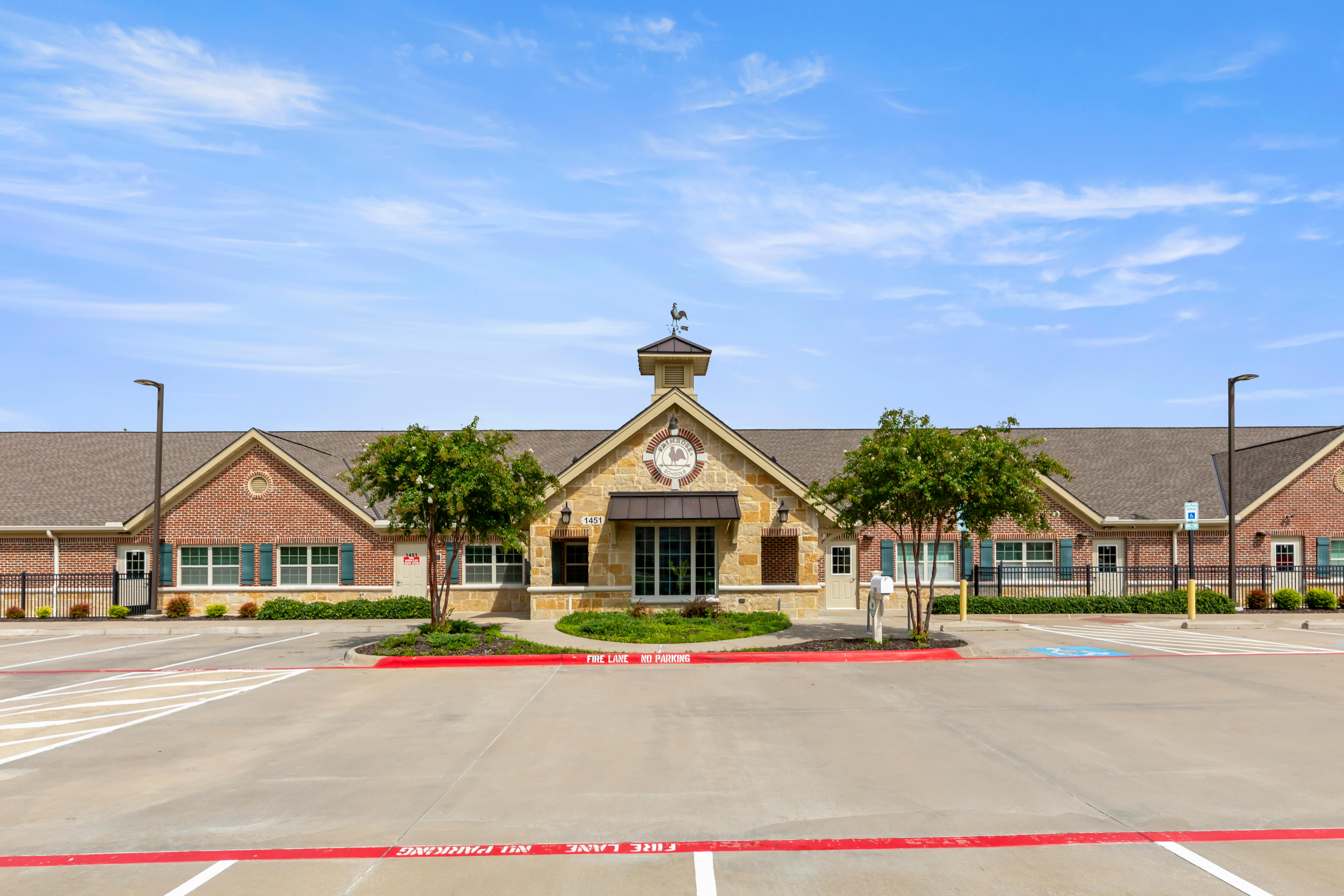 Front exterior of a single-story school building with a small cupola and weather vane