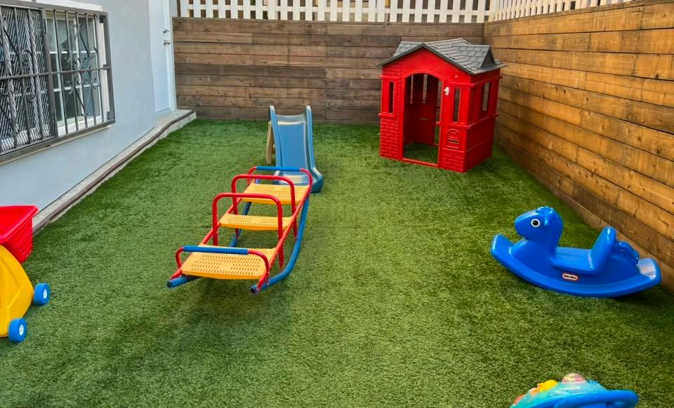 Plastic playground equipment on artificial grass in a backyard