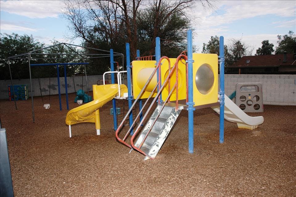 Playground with swings, yellow slide, and climbing structure