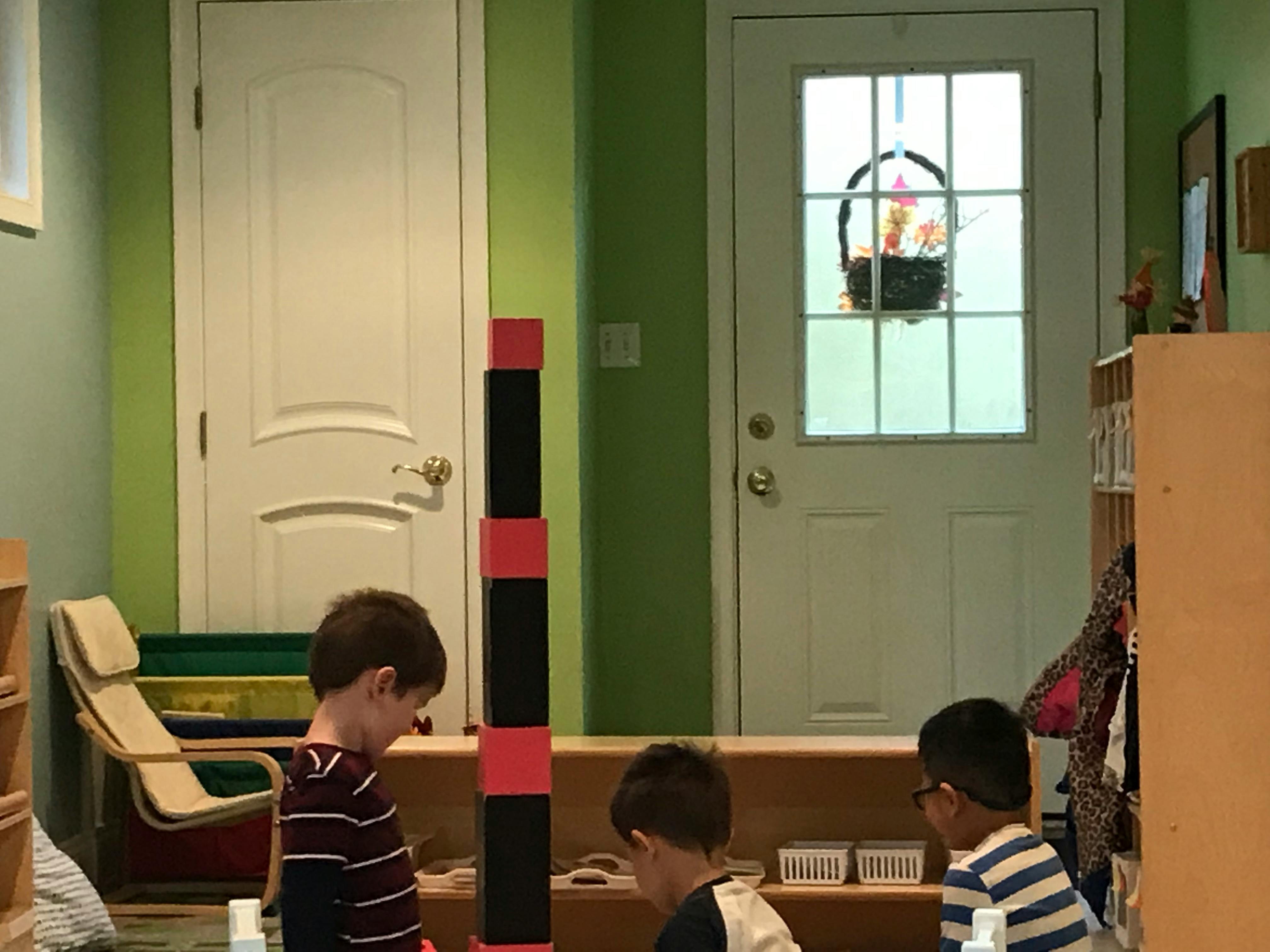 Two children looking at a tall block tower in a classroom