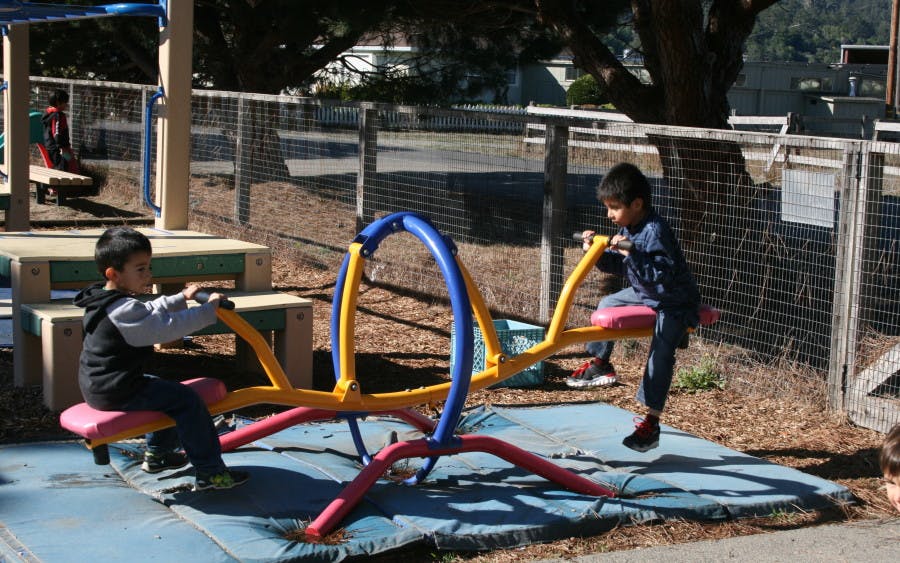 Two children on a seesaw on a playground
