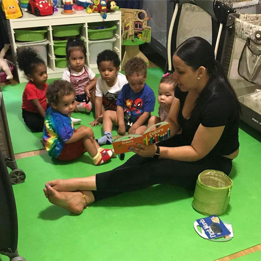 Person reading a book to a group of children sitting on the floor