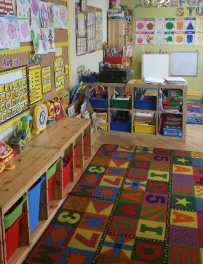 Classroom with colorful rug, storage shelves, and artwork on walls