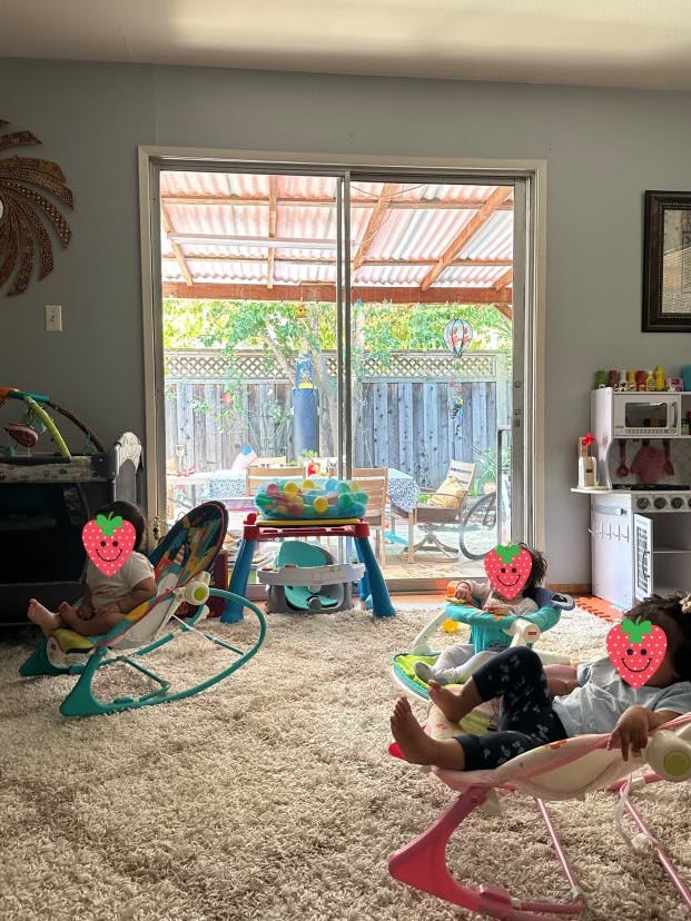 Three children in baby rockers on a carpeted floor