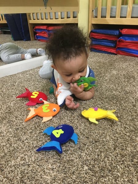 Child on carpet playing with colorful fish toys