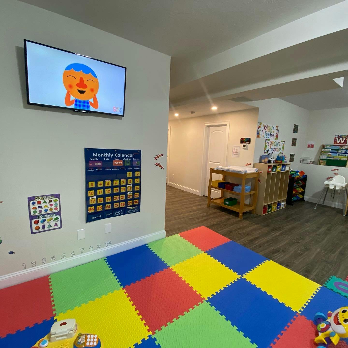 Playroom with colorful floor mats, a TV, and a monthly calendar on the wall