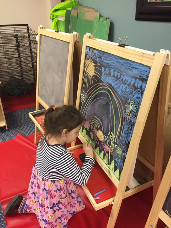 Child drawing on a chalkboard easel