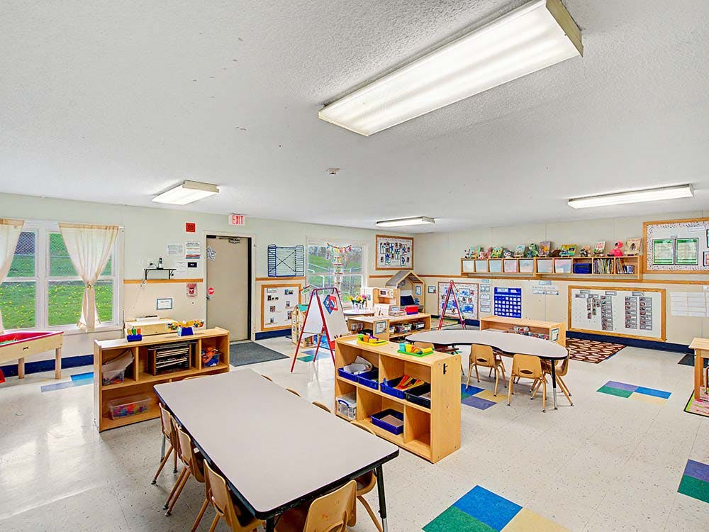 Classroom with tables, chairs, shelving units, and activity centers