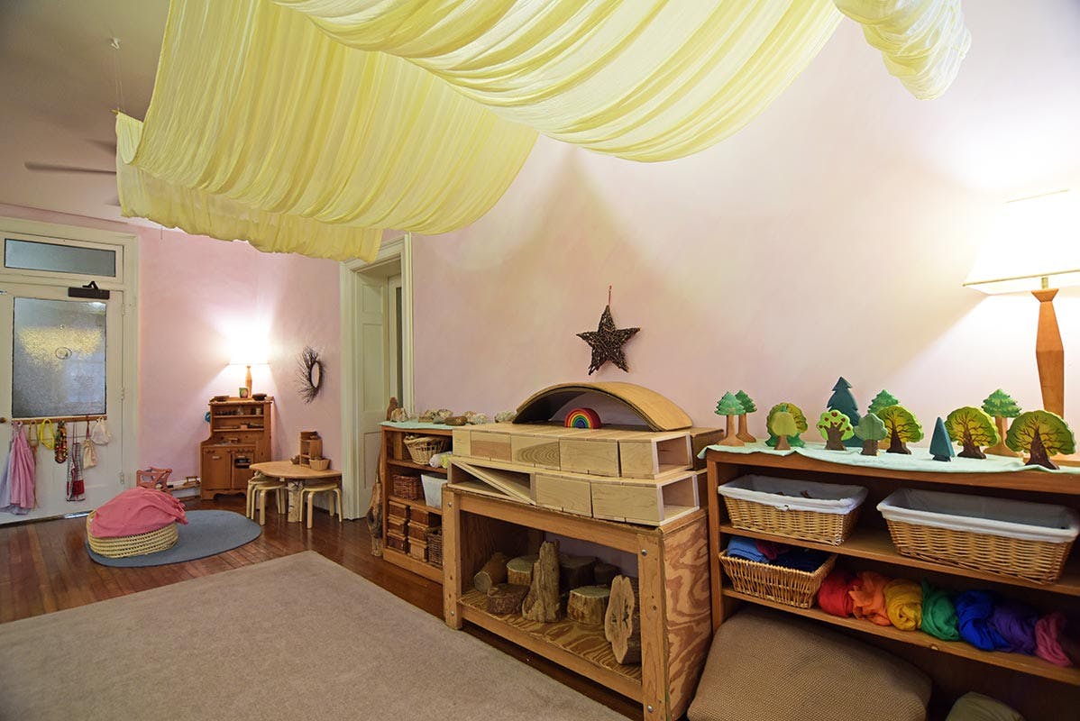Playroom with wooden shelves, toys, and yellow fabric draped from the ceiling