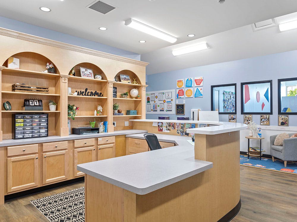 Reception area with a wooden desk and shelves displaying a "welcome" sign