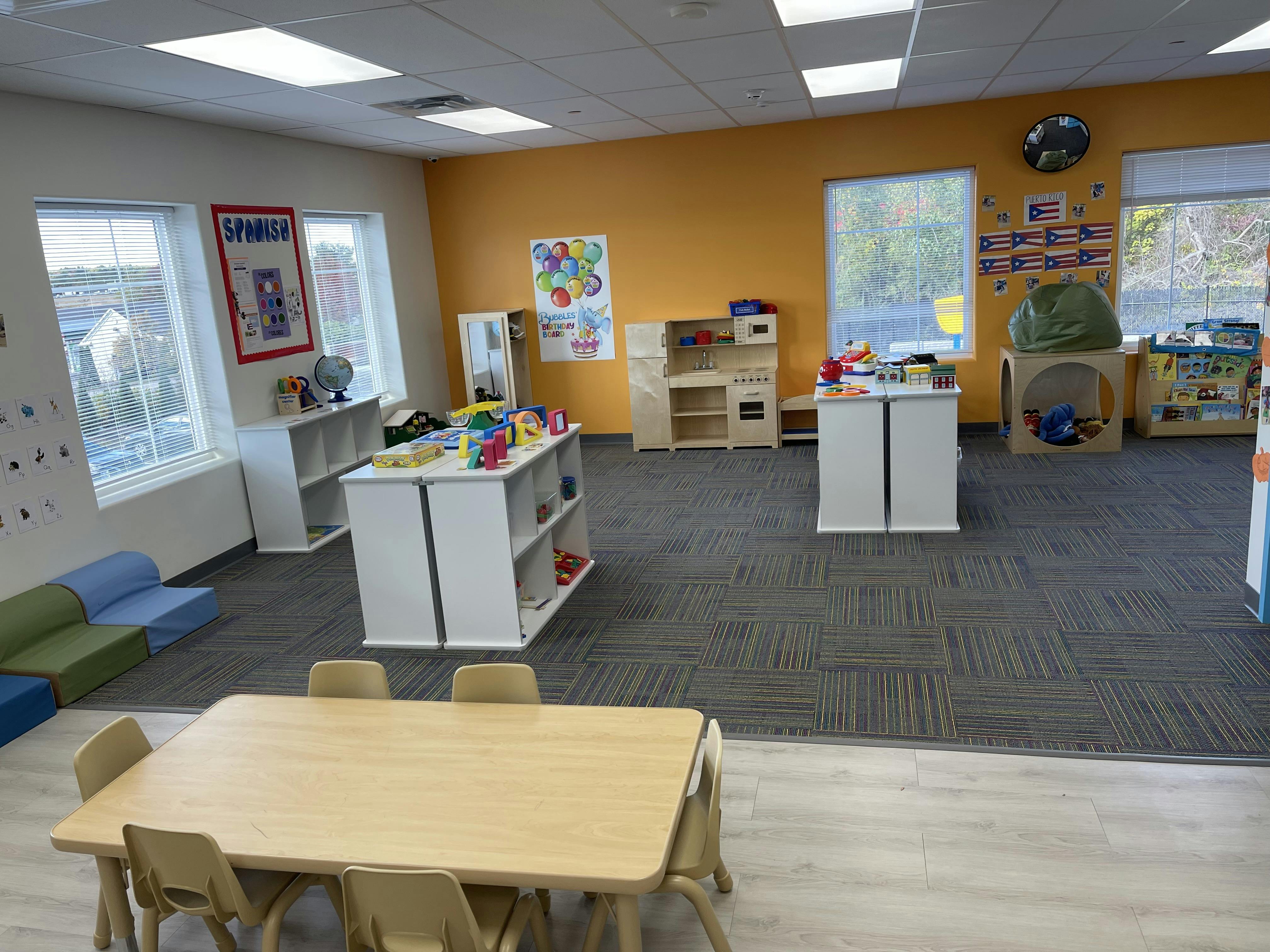 Empty classroom with tables, chairs, and play areas