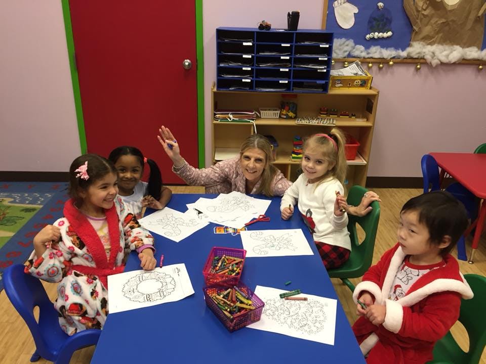 Adult and children coloring at a table in a classroom