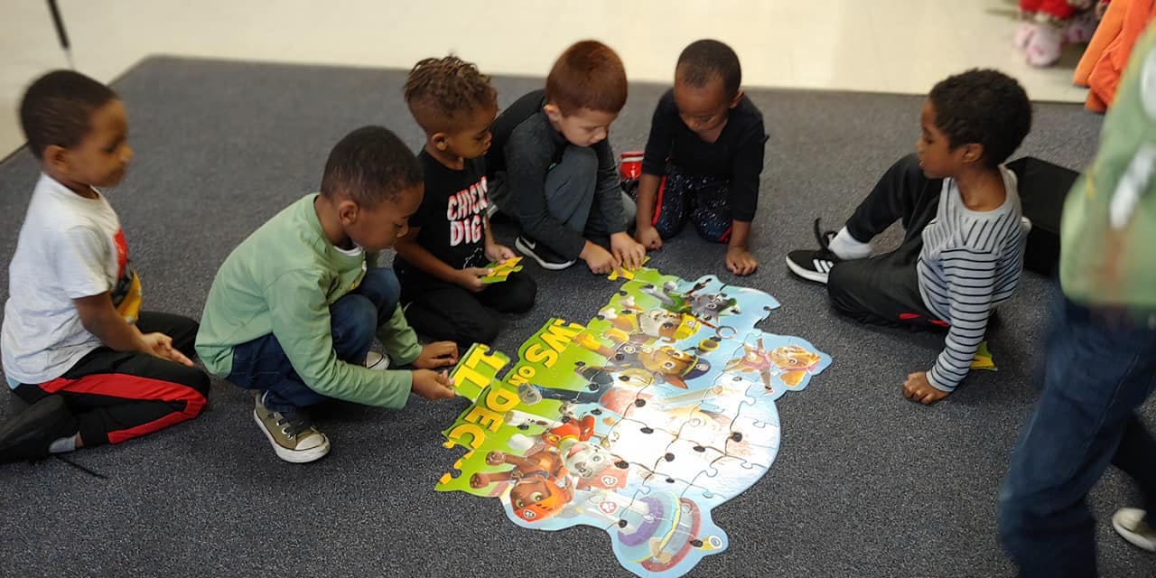 Children on floor assembling a large puzzle