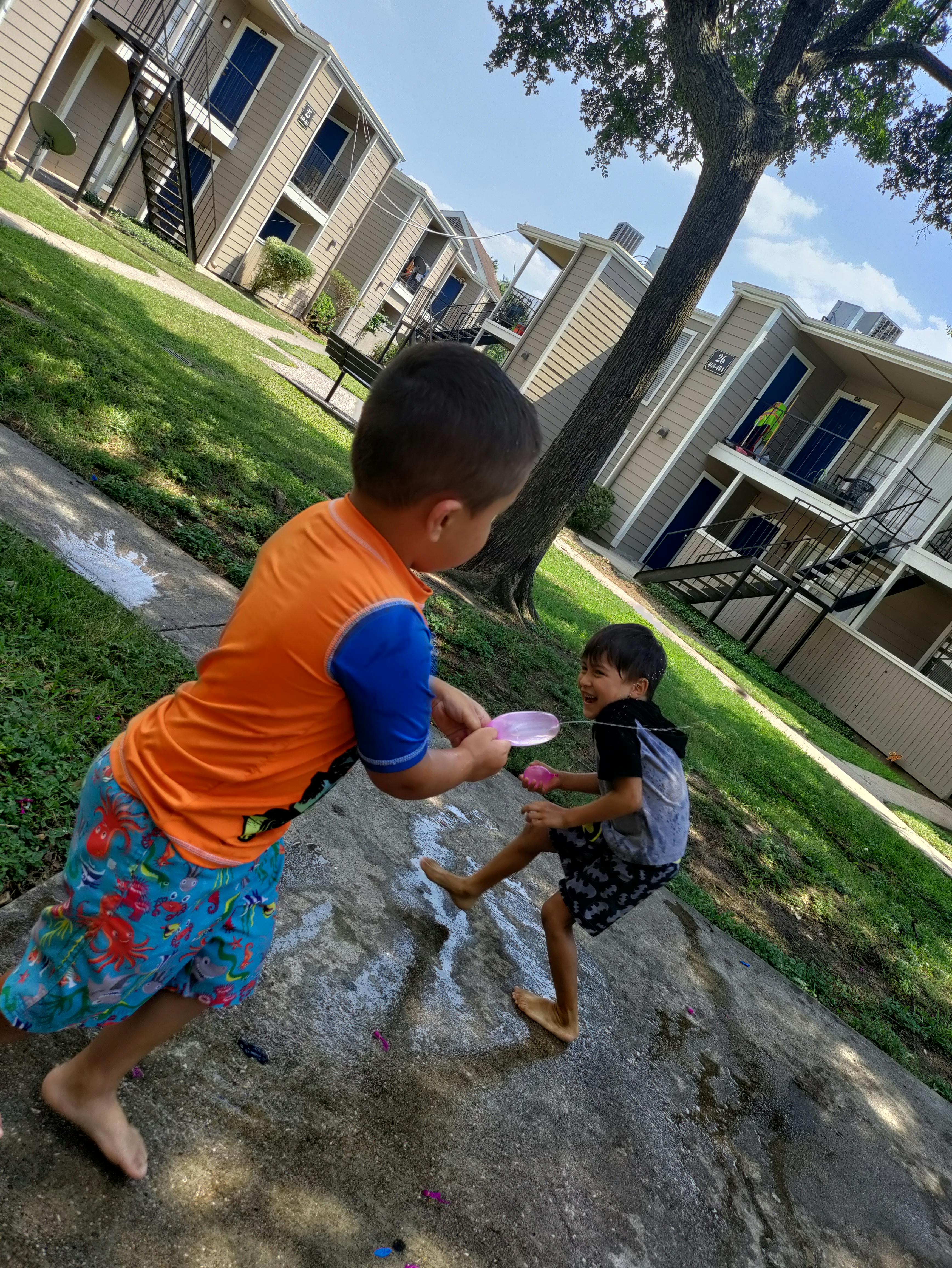 Two children playing with water balloons outdoors