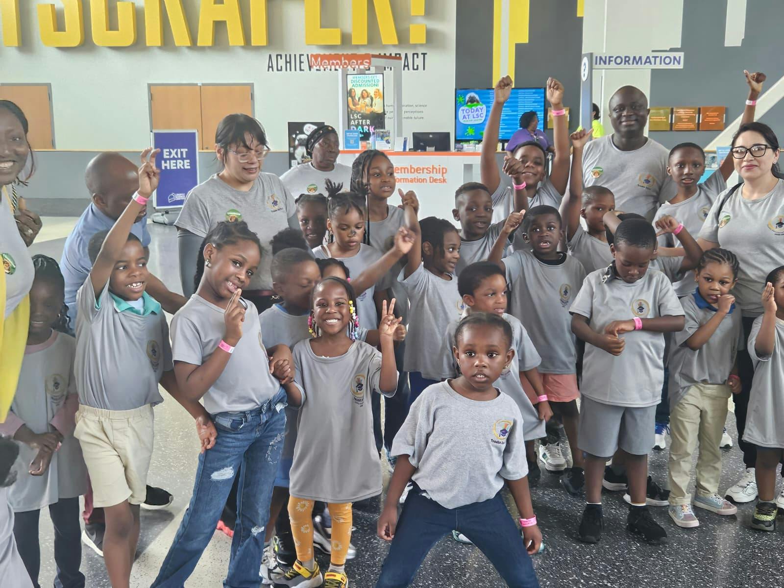 Group of adults and children with arms raised, some making peace signs