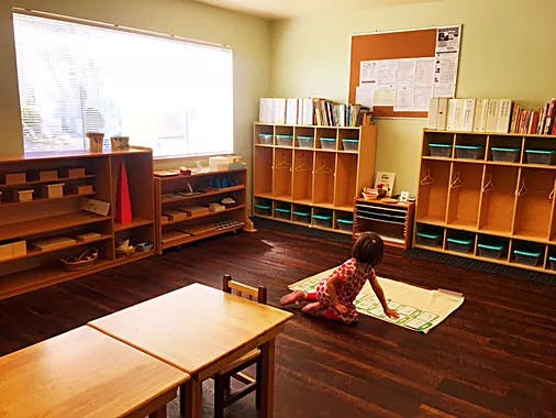 Child kneeling on a mat in a classroom
