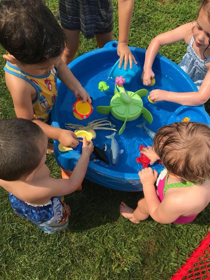 Children playing with toys in a blue water table