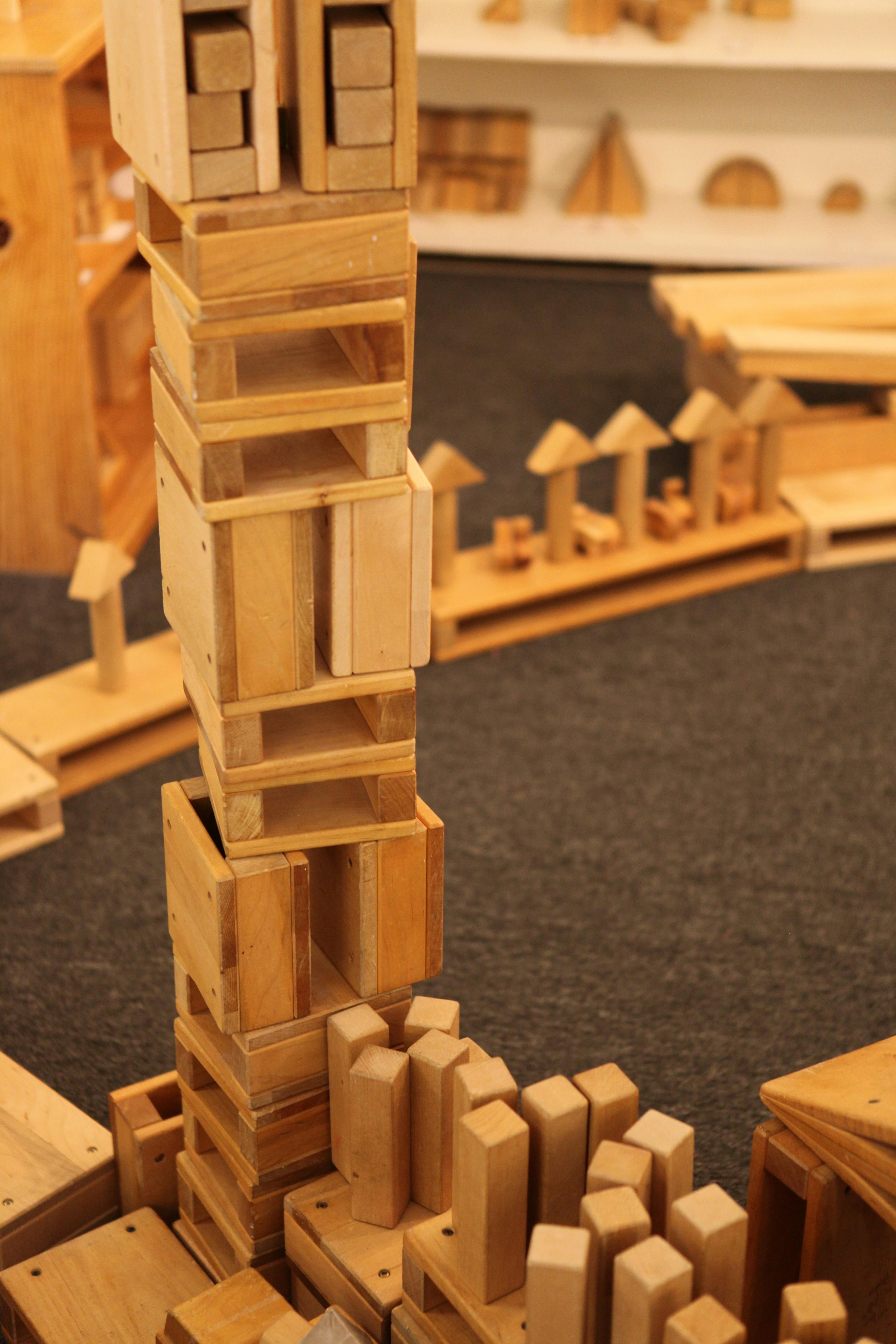 Tall tower built from wooden blocks with other blocks on the floor