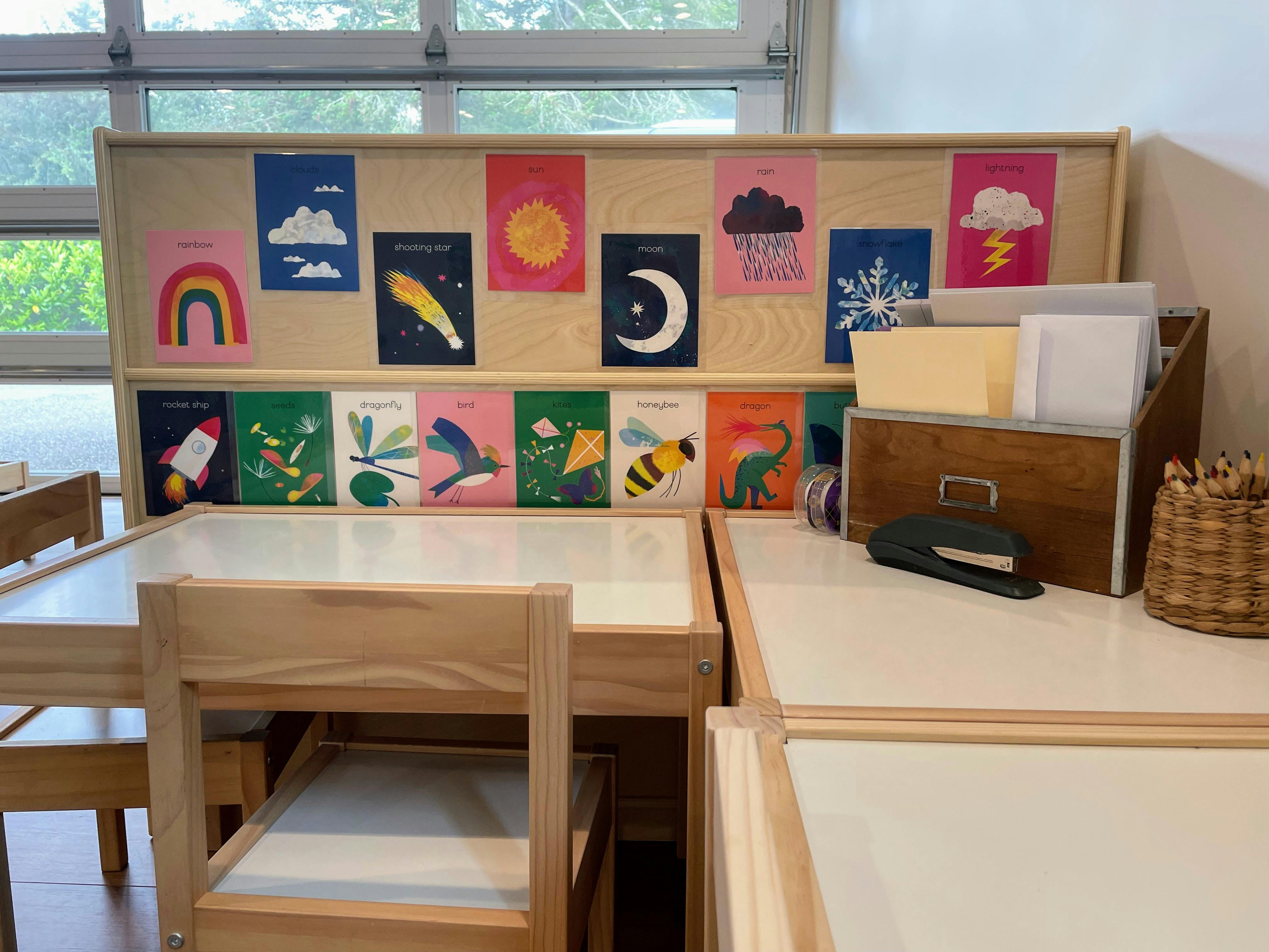 Classroom desks with a wooden divider displaying colorful educational posters