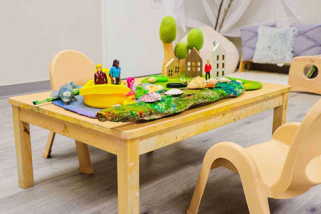 Small wooden table with miniature houses, trees, and figurines