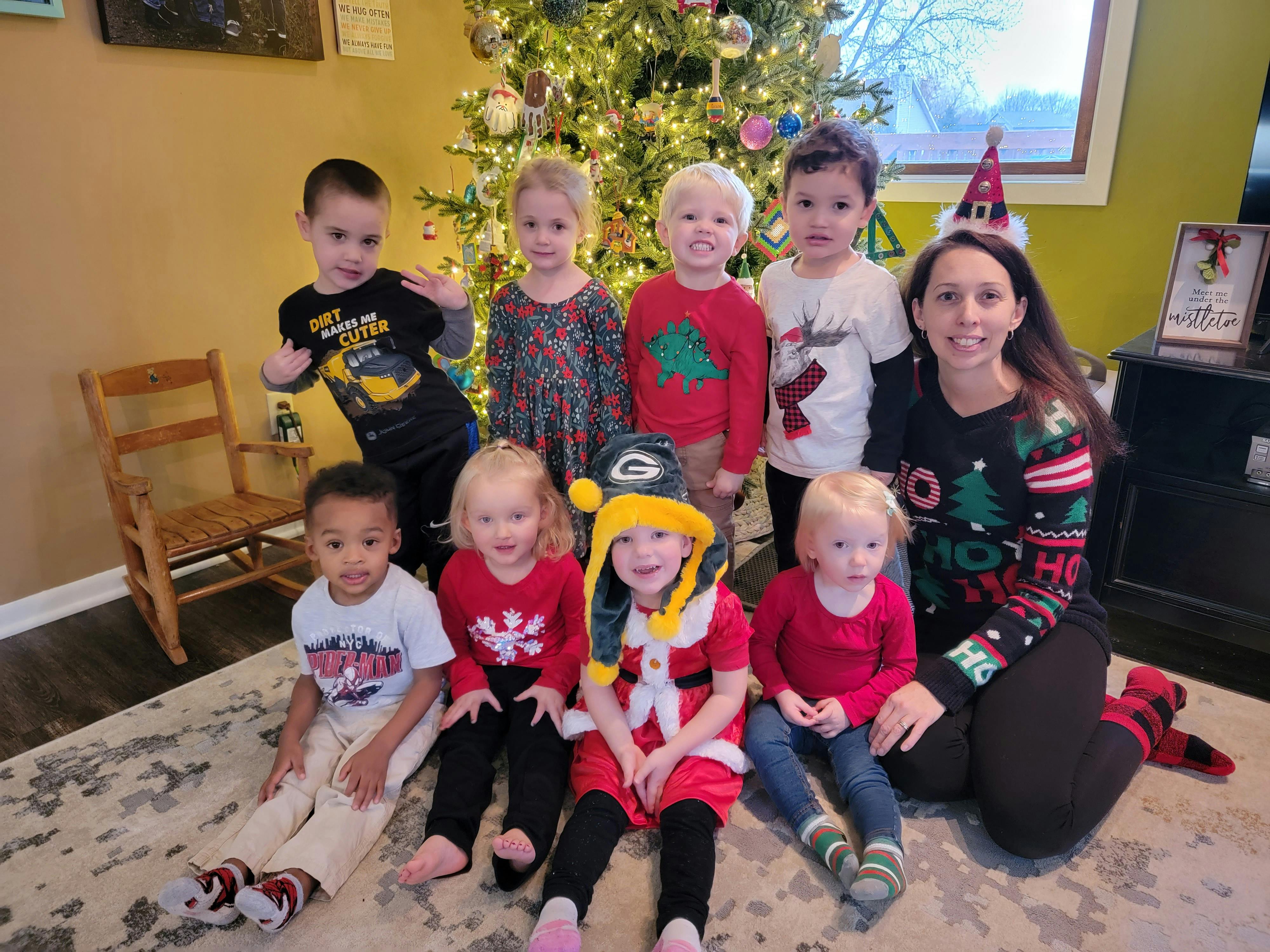Adult and multiple children posing in front of a Christmas tree