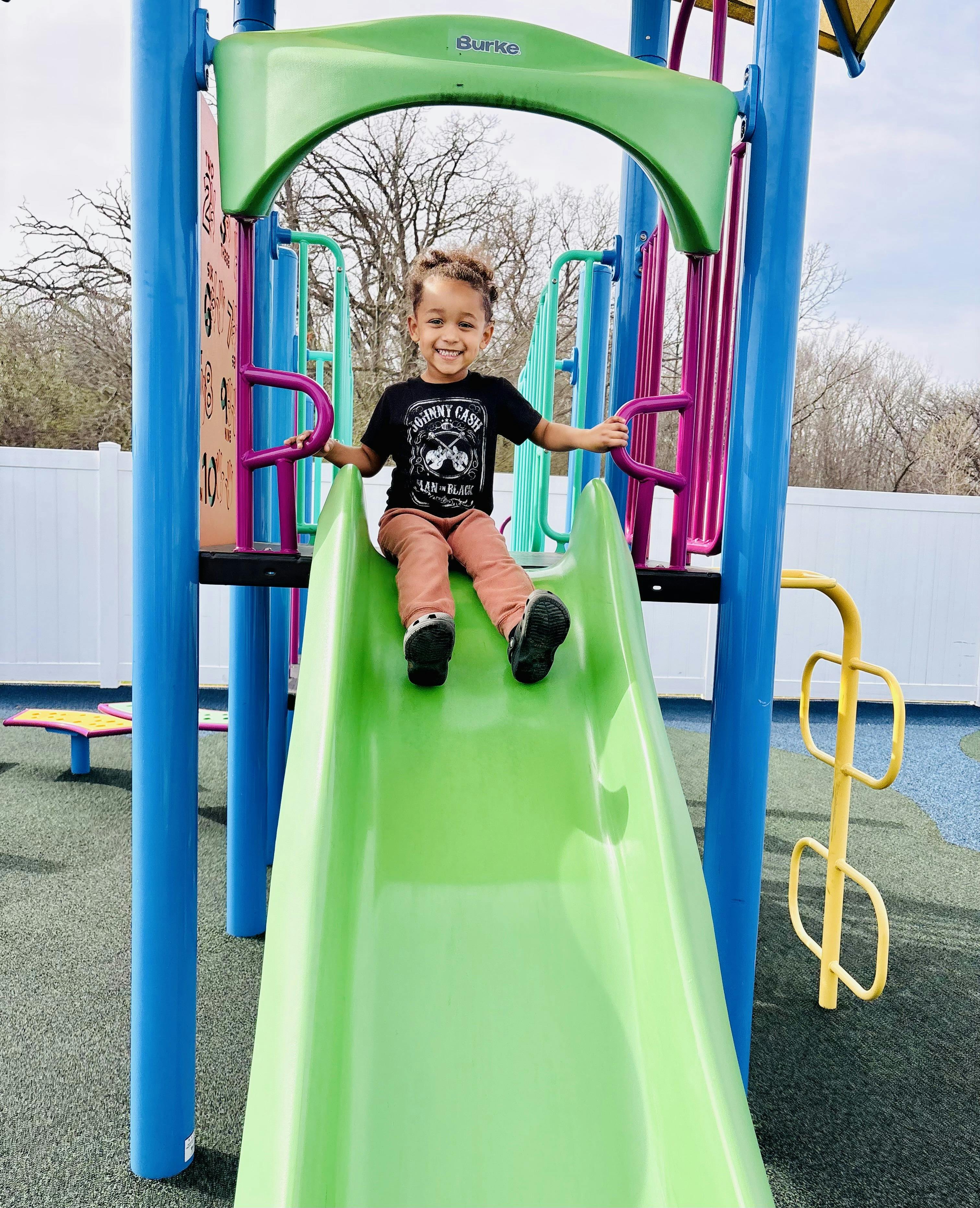 Child sitting on a green playground slide