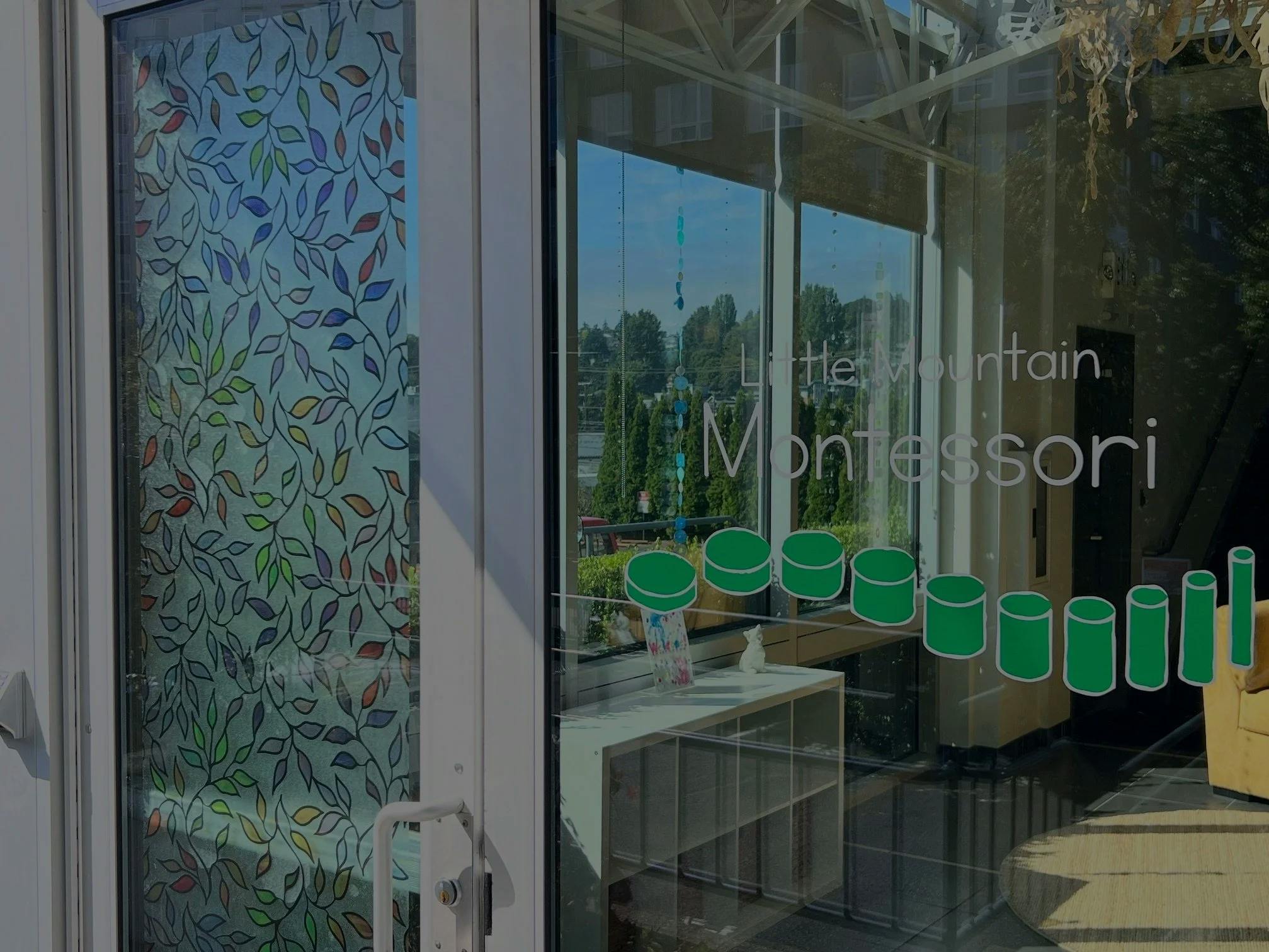 Entrance to a Little Mountain Montessori with leaf-patterned door and text on window