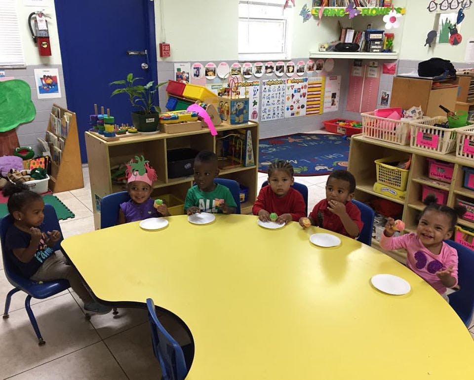 Children sitting at a yellow table in a classroom
