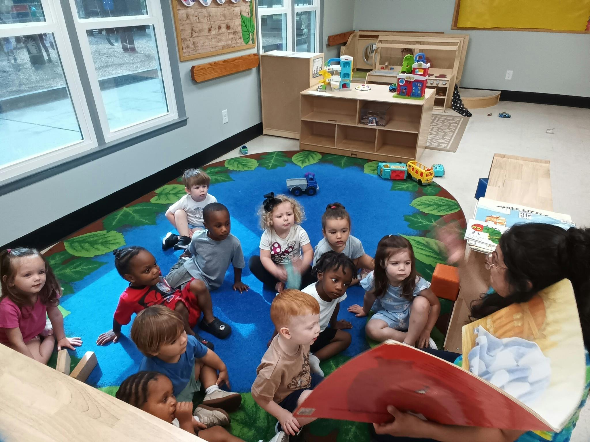 A person reading a book to a group of children in a classroom