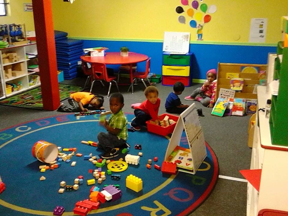 Children playing with toys on a colorful rug in a classroom