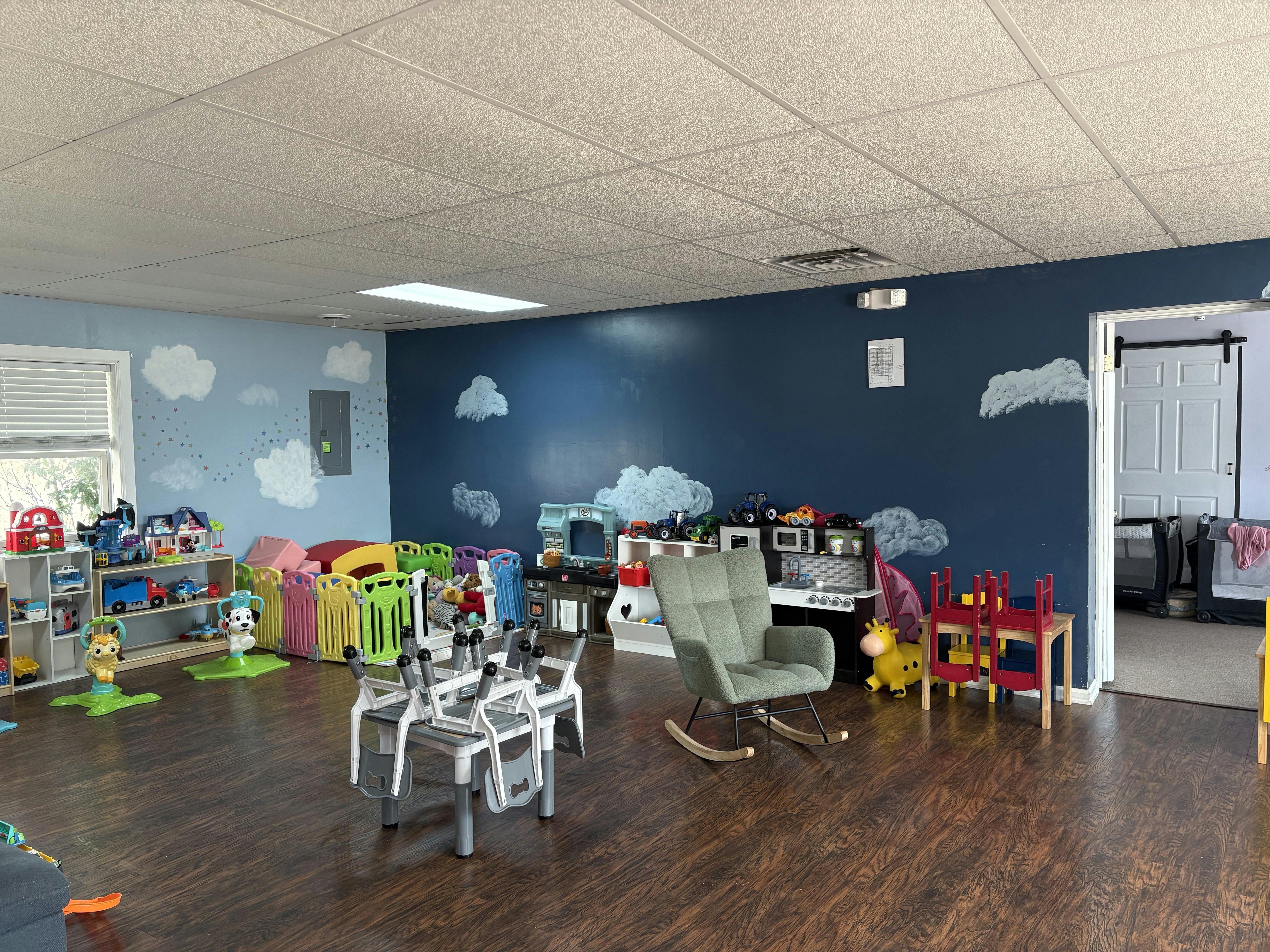 Playroom with blue walls, cloud decals, and various children's toys and furniture