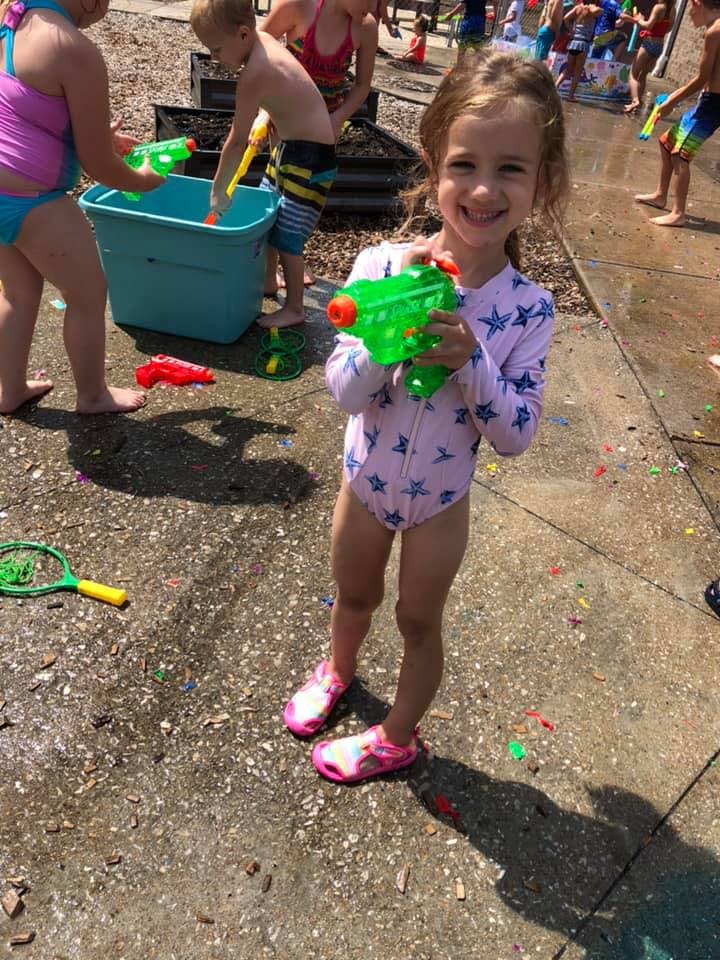 Child holding a water gun with other children in the background
