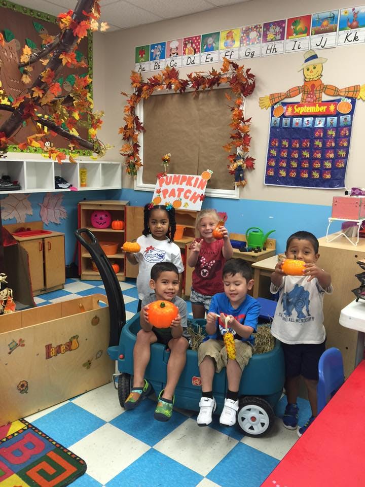 Children holding small pumpkins in a classroom