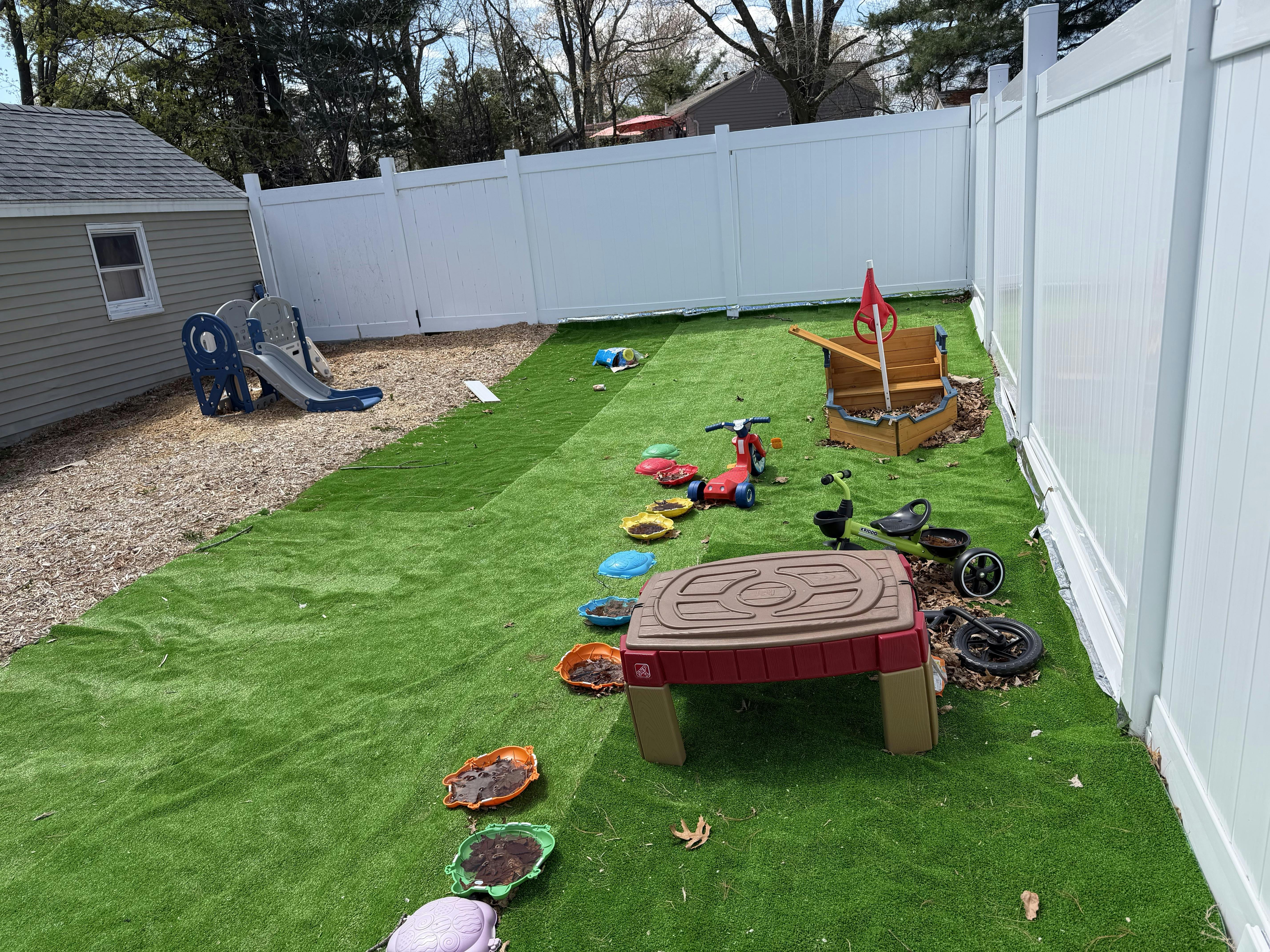 backyard with artificial turf, children's playset, slides, and sandpit