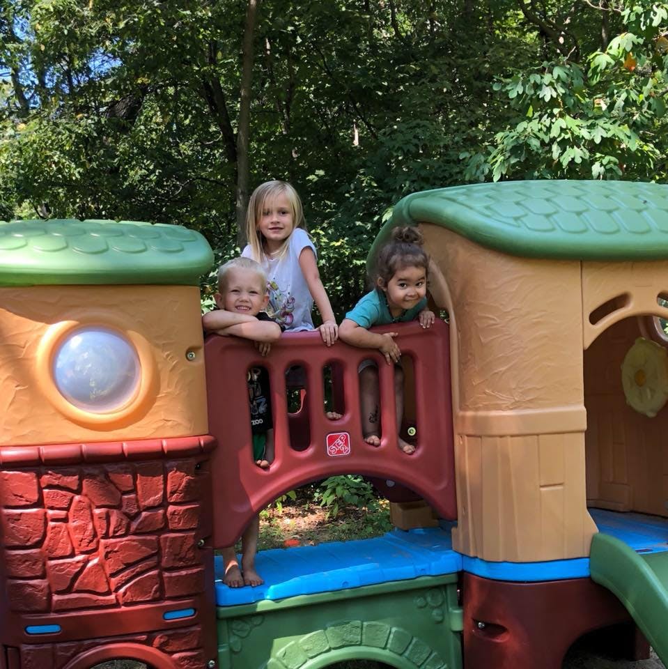 Three children playing on a colorful outdoor play structure