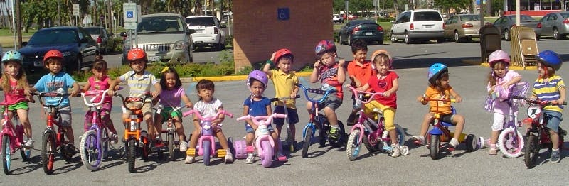 Group of children wearing helmets and riding bicycles and standing with bicycles