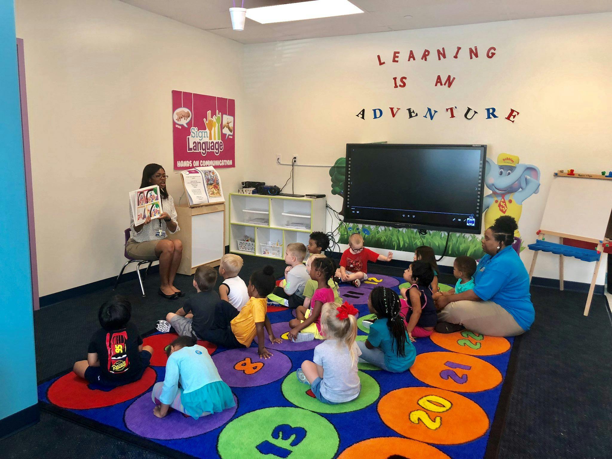 Two people reading to a group of children in a classroom