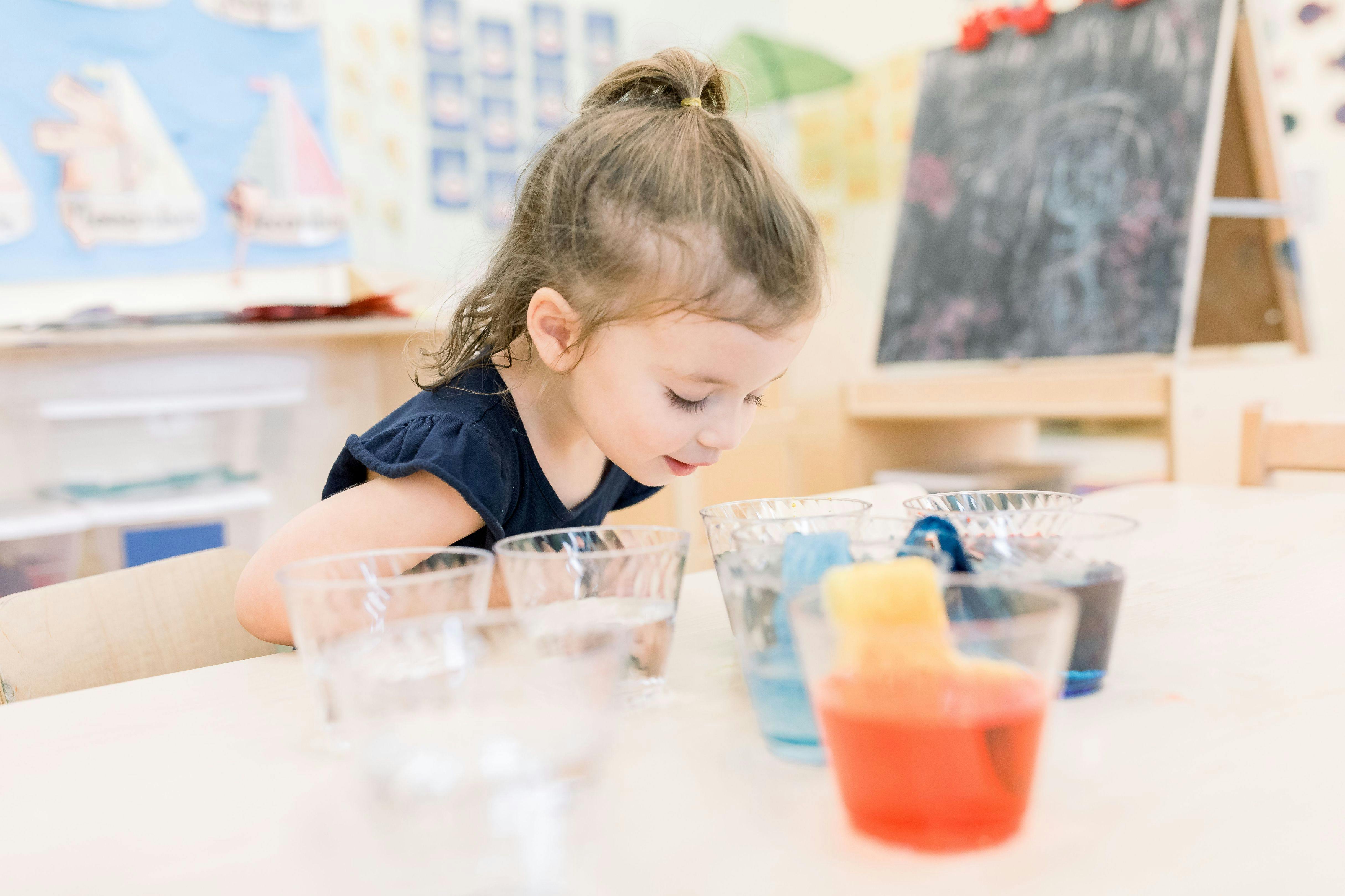 Child looking at plastic cups of colored water on a table
