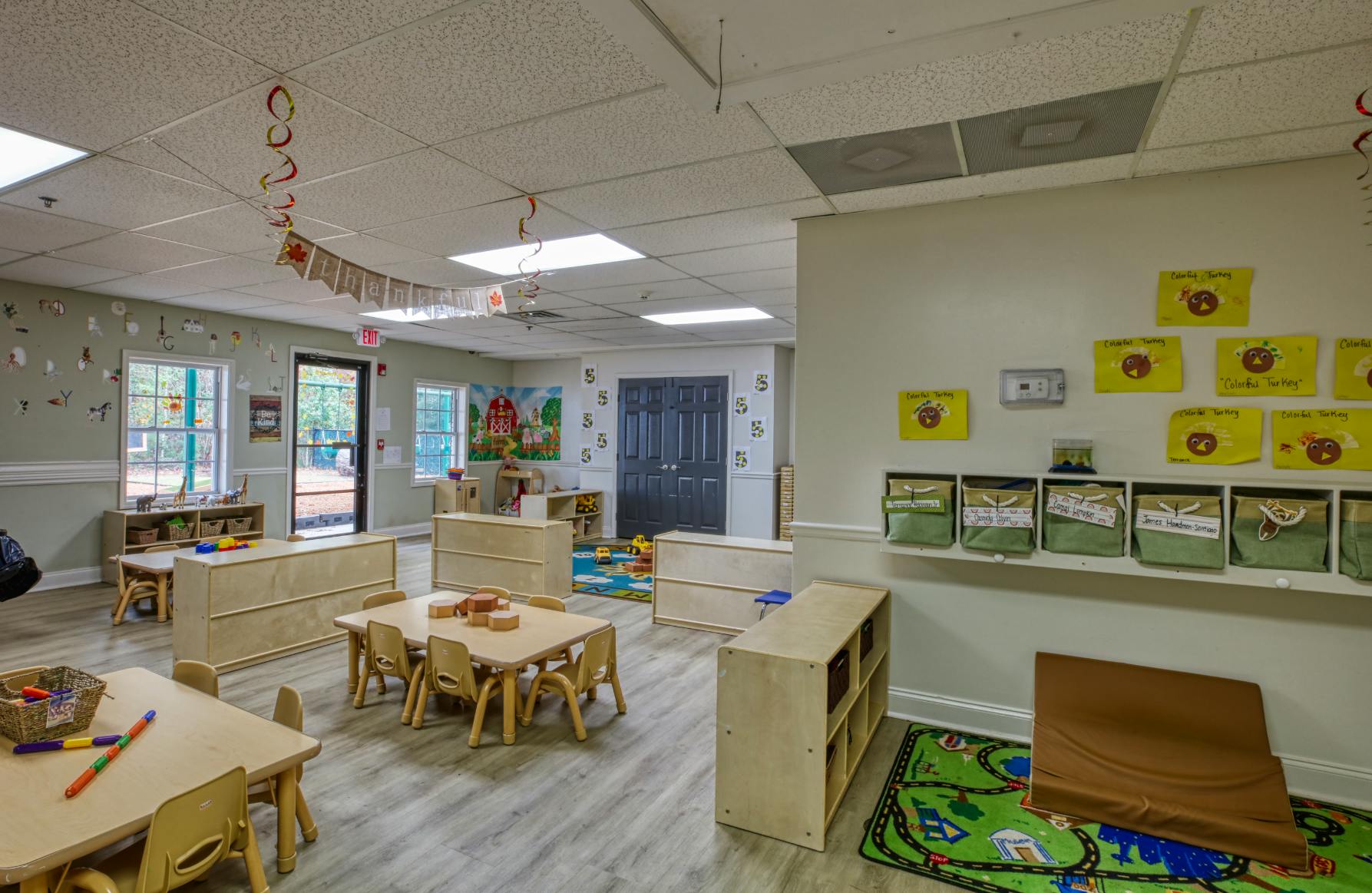 An empty classroom with small tables and chairs, and wall decorations