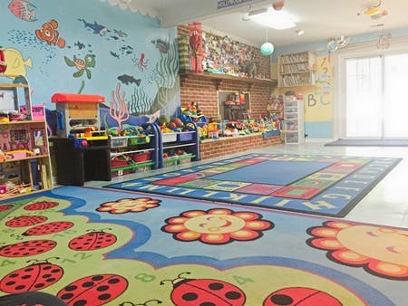 Playroom with colorful rugs, toys, and a mural