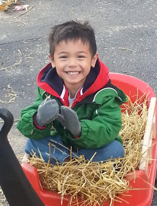 Child in a red wagon filled with hay