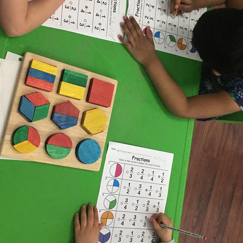 Children working on fraction worksheets with a colorful fraction puzzle