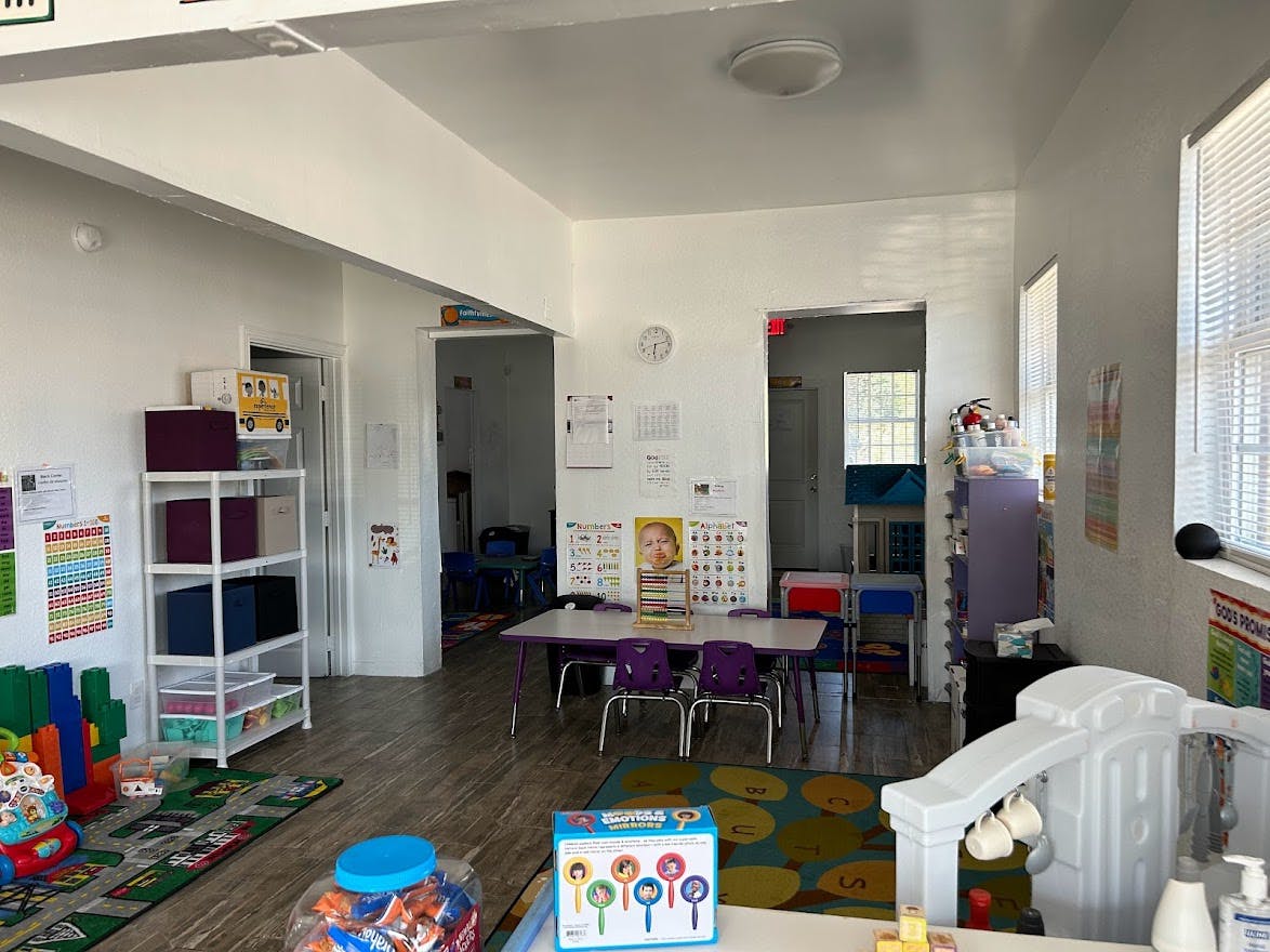 A classroom with small tables and chairs, shelves, and colorful rugs