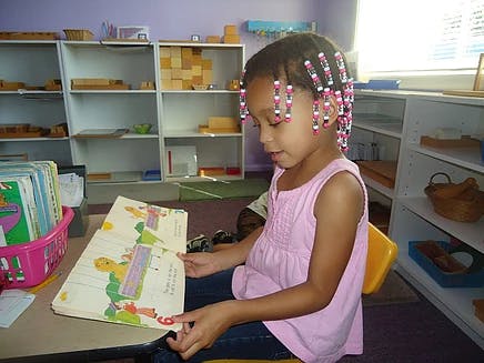 Child reading a book in a classroom