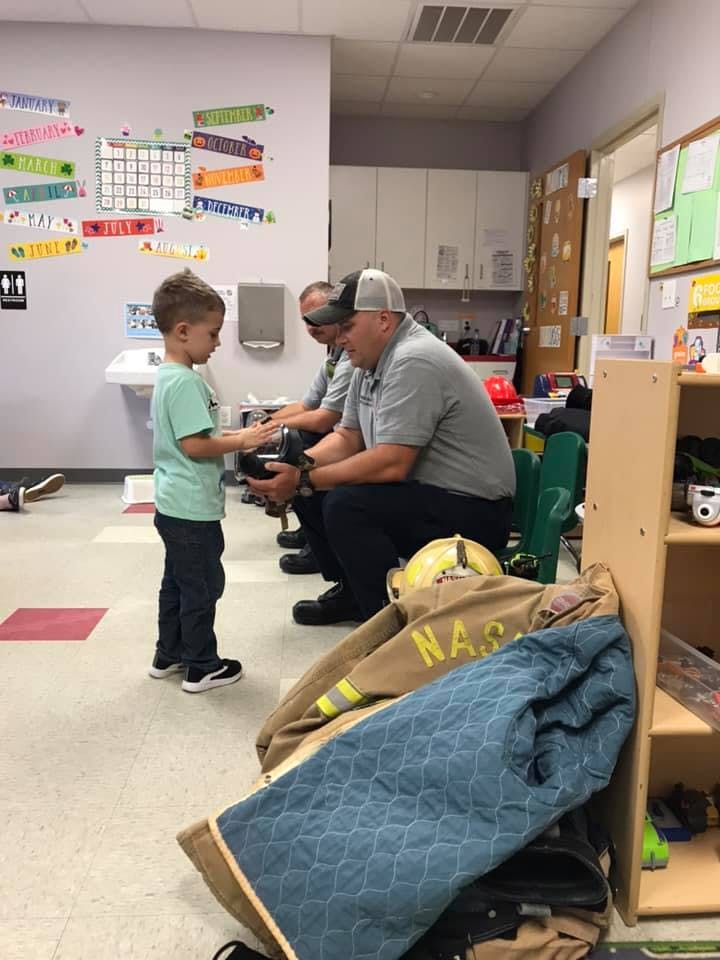 Adult showing a child an object in a classroom